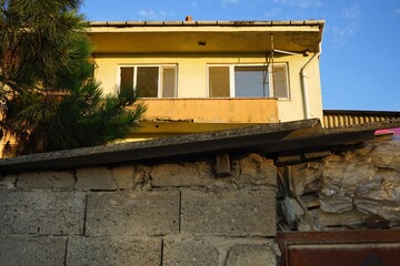 Alter gemauerter Schuppen mit Pultdach vor einem Wohnhaus mit Balkon in Beige und Naturfarben vor...