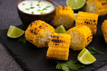 Grilled corn, lime on a dark background