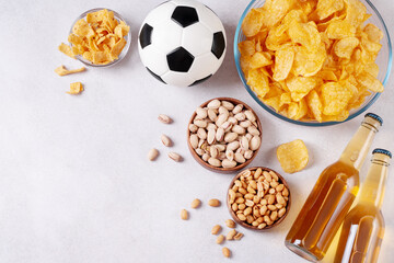 Beer and snack on gray table with football ball, football game night food, copy space