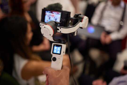Professional videographer in black hoodie holding professional camera on 3-axis gimbal stabilizer. Filmmaker making a great video with a professional cinema camera. Cinematographer.