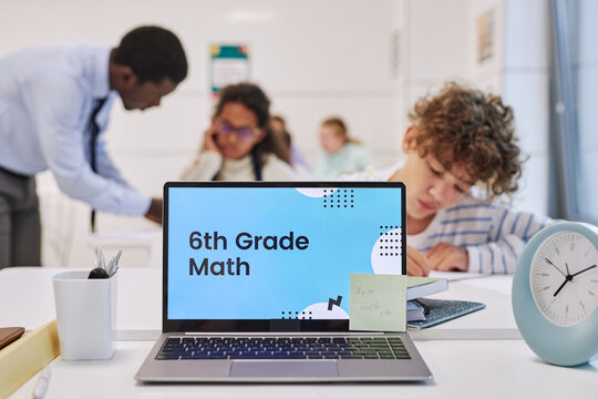 Background image of open laptop in school classroom with 6th Grade math screen, copy space