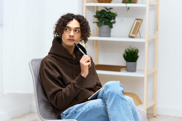 handsome guy sit on a chair with a notepad and a writing pen isolated background