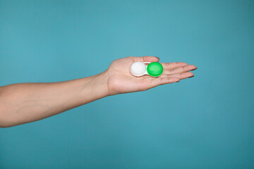 Lady holding case for contact lenses. Closeup image of container for contact lenseson blue background in studio.