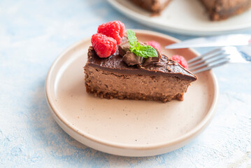 Fototapeta na wymiar delicious sweet chocolate cheesecake cake in a restaurant with raspberries and mint leaf on a plate