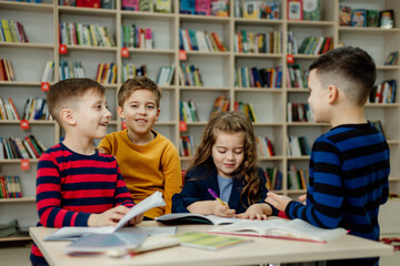 Fototapeta premium school children in the library reading books, doing homework, prepare a school project for lessons