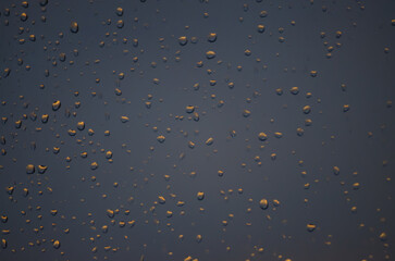 rain drops on the window on the sunset. blue background with orange drops. 