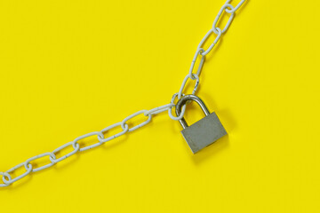 The padlock and chains on yellow background. Flat lay, top view with copy space for text.
