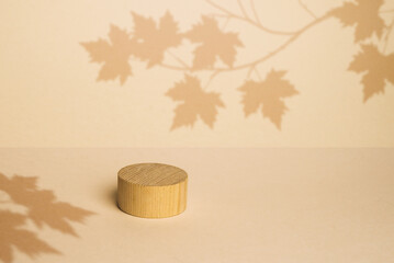 brown box made of precious wood, block, cylindrical podium, branch with maple leaves on a...