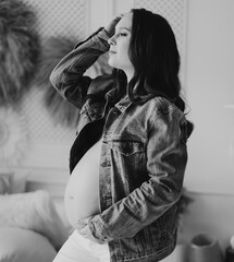 black and white. a beautiful pregnant woman in a denim jacket with a naked tummy