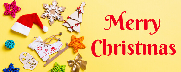 Merry Christmas text. Top view Banner of Christmas decorations and Santa hats on yellow background. Happy holiday concept with copy space