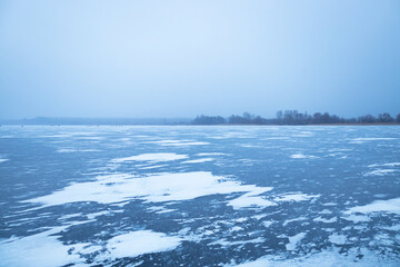 Beautiful winter evening landscape overlooking a river covered with ice and strewn with snow, winter background