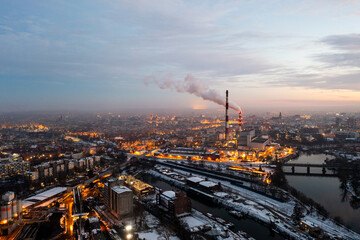 Aerial view of the evening Polish city of Wroclaw, the panorama of the old European city from a height. In the distance, above the city, large smoking chimneys of a thermal power plant can be seen.