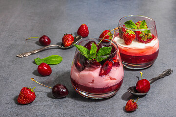 Delicious Italian dessert panna cotta with sweet cherry sauce, fresh strawberries and mint leaves