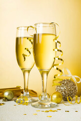 Champagne glasses and christmas decor on colored holiday background. Flat lay New Year decorations