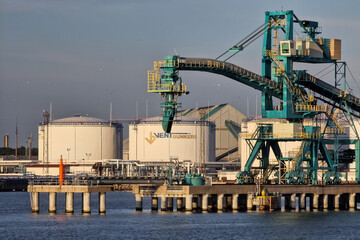 Ventspils, Latvia - August 14, 2022: Big crane and large white oil fuel tanks in the port of Ventspils.