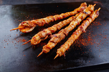 Traditional grilled torches with bacon and spicy marinade wrapped around a wooden skewer and served...