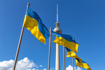 Ukrainian flags near adminisrative building in the center of Berlin on Alexanderplatz. - obrazy, fototapety, plakaty