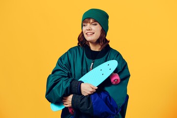 a joyful woman stands on a yellow background in a fashionable jacket and hat from the 90s and...
