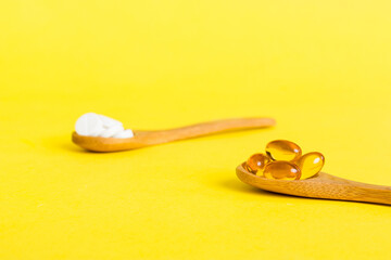 Vitamin capsules in a spoon on a colored background. Pills served as a healthy meal. Red soft gel vitamin supplement capsules on spoon