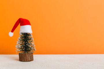 One small Christmas tree with santa hat on colored background. new year decoration with copy space