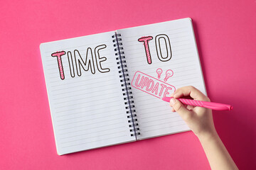 Human hand with pen writing text TIME TO UPDATE on pink background