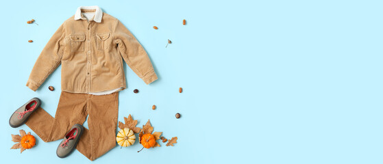 Stylish autumn baby clothes on blue background with space for text