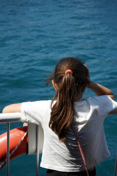 M&auml;dchen an der Reling einer Bosporus F&auml;hre mir Haarband in der Farbe des Rettungring im Sommer bei Sonnenschein in Istanbul in der T&uuml;rkei