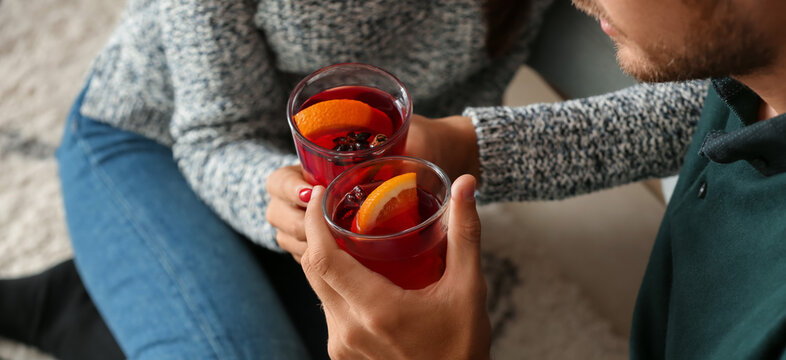 Young couple drinking delicious mulled wine at home, closeup