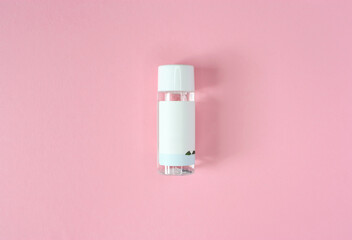 Glass transparent mini tonic, essence, cleanser, lotion, micellar water skin care bottle with blank white paper label and twist off white cap. Isolated on pink background. Beauty product mock up.