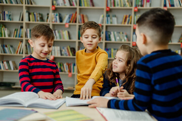 school children in the library reading books, doing homework, prepare a school project for lessons