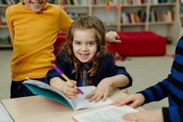 Fototapeta premium school children in the library reading books, doing homework, prepare a school project for lessons