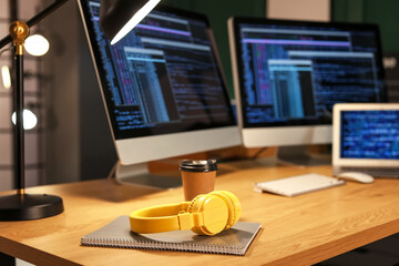 Headphones, coffee and notebook on programmer's table