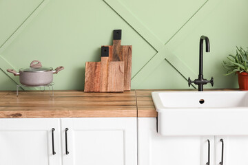 Counters with cutting boards and sink near green wall