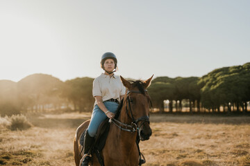 Fototapeta premium backlit photo of a young rider riding a horse