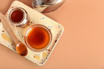 Board with jar and bowl of tasty maple syrup on color background