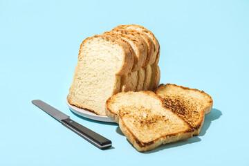 Plate with toasts and knife on color background