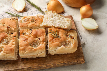 Wooden board with tasty Italian focaccia on light table, closeup