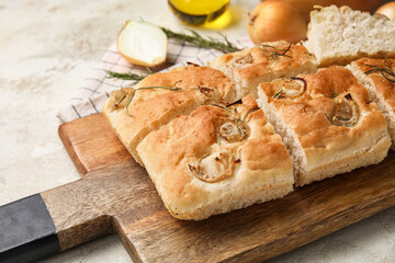 Wooden board with tasty Italian focaccia on light table, closeup