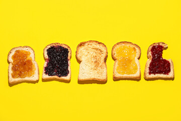 Pieces of toasted bread with different jams on yellow background