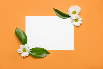 Blank paper sheet with daisy flowers and leaves on orange background