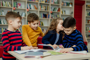 Fototapeta na wymiar school children in the library reading books, doing homework, prepare a school project for lessons