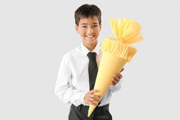 Little boy with yellow school cone on light background