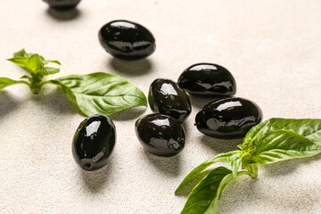 Tasty black olives and basil on light background, closeup