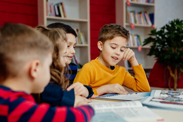 school children in the library reading books, doing homework, prepare a school project for lessons