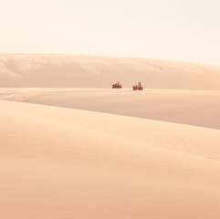 Fototapeta na wymiar quads driving through the sand dunes in the desert