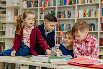 school children in the library reading books, doing homework, prepare a school project for lessons