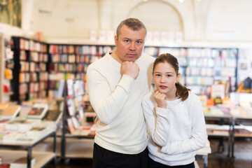 Portrait of pensive young man and preteen girl in modern bookstore