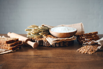 Bread, grains, ears of wheat and flour on a wooden background, bakery advertising banner