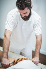 Close up the masseur performs of Maderotherapy, anticellulite therapy with an extended wooden rolling pin