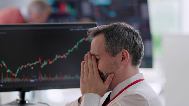 Mature financial analyst looking at computer with graphs and feeling frustrated